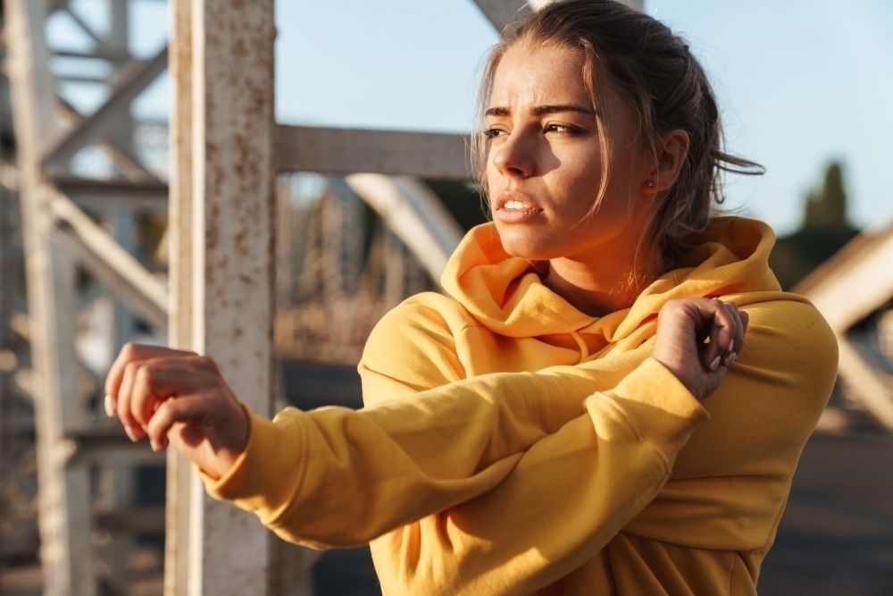 Photo of a beautiful amazing young sports fitness woman make stretching exercises outdoors.